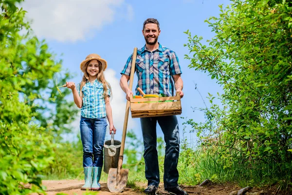 Spring gardening checklist. Father and daughter with shovel and watering can in garden. It is time to plant prepare beds and care for lawn. Pick out flats favorite plants. Garden works. Spring garden