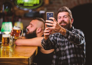 Çevrimiçi iletişim. Arkadaşlarınızın sosyal ağlarına selfie gönderin. Barda bira içen adam. Barda harika bir akşam hatırlamak için selfie fotoğrafı çekin. Adam sakallı hipster akıllı telefon tutun. Selfie konseptini çekmek