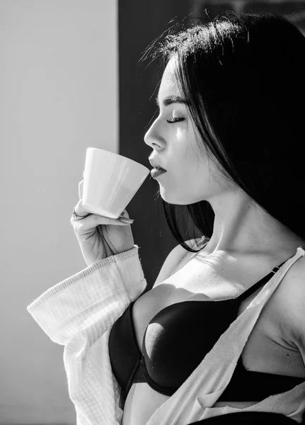 喝奶油卡布奇诺。早上的仪式女孩性感的乳房在窗台附近喝咖啡。有吸引力的女性内衣放松在家里。完美的咖啡时间。但第一杯咖啡宁静与和平 — 图库照片
