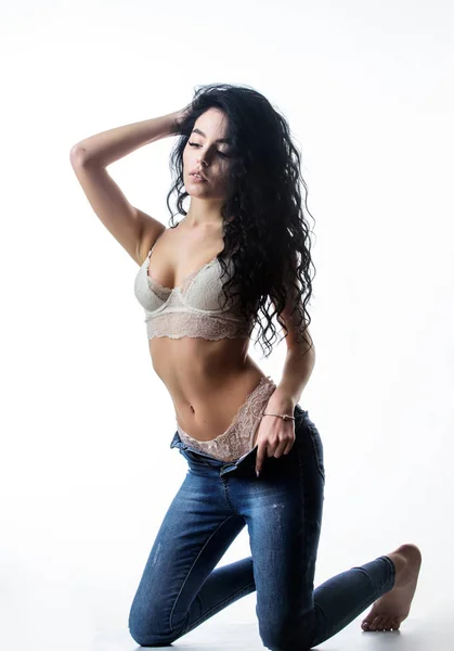Fashion beauty. Diet and fitness.. woman with perfect body relax. sexy woman in jeans and bra. erotic games. Isolated on white. sensual girl with curly hair. Flexible body. Long and healthy hair Stock Picture