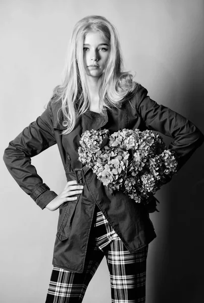 Mulher loira cabelo posando casaco com flores buquê. Roupas e acessórios. Menina moda modelo casaco de desgaste para a primavera e outono temporada. Trench casaco tendência da moda. Casaco elegante. Deve ter conceito. — Fotografia de Stock