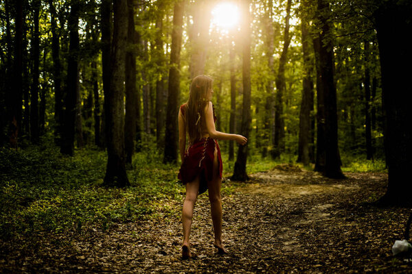Amazon woman. sexy witch. sexy girl in leather suede clothes. ethnic tribal fashion. deep forest. cougar female. wild woman in forest. female silhouette through the sun rays. Sexy young female.