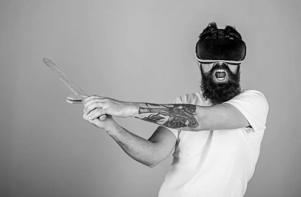 Concept de joueur VR. Homme avec barbe en lunettes VR, fond bleu clair. Guy avec affichage monté sur la tête et l'épée jouer jeu de combat en VR. Hipster sur le visage criant profiter du jeu en réalité virtuelle — Photo