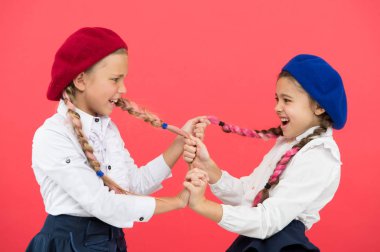 Zorbalık ve saldırganlık. Yaramaz çocuklar pembe arka planda at kuyruğu çekiyorlar. Zorbalık davranışları olan küçük kızlar bir çatışmayla savaşıyor. Okulda zorbalık. Zorbalığı durdurma zamanı
