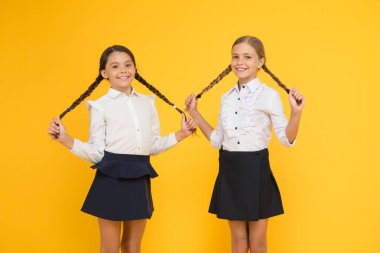 Okul saç modeline geri dön. Sarı arka plan üzerinde uzun saç modeli ile Sevimli küçük kızlar. Örgülü saç stili tutan sevimli küçük çocuklar. Saç stilinizin tüm gün sürmesini sağlamak