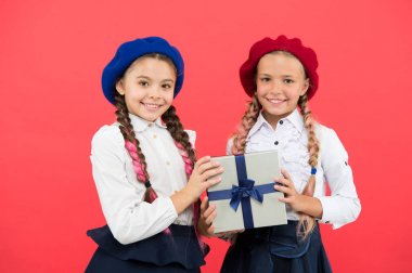 Dostluk onların gerçek hediyesidir. Pembe arka planda doğum günü hediyesi tutan küçük çocuklar. Küçük kızlar sarılmış hediye kutusuyla gülümsüyorlar. Mutlu çocuklar 1 Eylül için okul mevcut hazırlanıyor