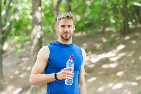 Refreshing drink. Man athletic sportsman hold bottle water. Athlete drink water after training in park. Vitamins and minerals. Man athlete sport clothes care about water balance. Healthy lifestyle