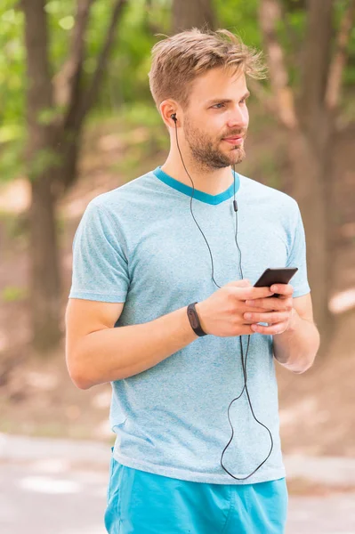 Living a mobile lifestyle. Athletic man tracking his activity with mobile phone app. Sportsman using mobile device and fitness watch for training. Fit guy syncing fitbit data through mobile internet