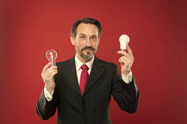 Man bearded businessman formal suit hold light bulb on red background. Symbol of idea progress and innovation. Idea for business. Environment friendly idea. Genius idea. Light up your business