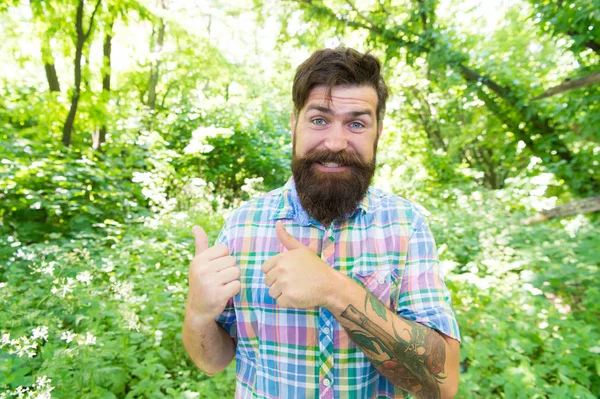 Living a happy life. Happy hipster giving thumbs ups gesture on natural landscape. Emotional guy with long mustache and beard hair on happy face. Bearded man with happy emotions in summer style