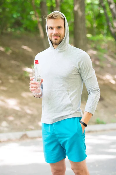 充满能量。戴帽子的人喝水。锻炼后清凉的维生素饮料。运动的人与水瓶。运动员在公园里训练后喝水。护理身体水化。体育与健康 — 图库照片