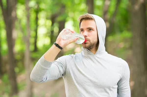 Susuz kalmamak. Sporcu parktaki eğitimden sonra su içer. Vücut sıvısına dikkat et. Spor ve sağlık. Kapüşonlu adam su içiyor. Antrenmandan sonra vitamin içeceği. Su şişeli atletik adam. — Stok fotoğraf