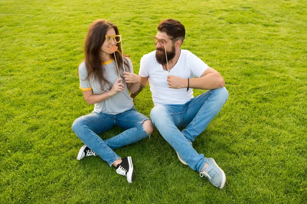 愛陽気な若者ブースの小道具のカップル。カップルデート楽しい緑の芝生を持つ気楽なカップル。感情的な人々夏のエンターテイメント。男はヒップスターとかわいい女性陽気な顔をあごひげ。青少年の日 — ストック写真