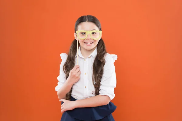 Mindig kérdés. iskolás lány egyenruhában. gyermek partiszemüveggel. okos és intelligens kölyök narancssárga háttérrel. Vissza az iskolába. Vicces tanulmány. tudásnap. Boldog gyermekkort. kislány diák — Stock Fotó