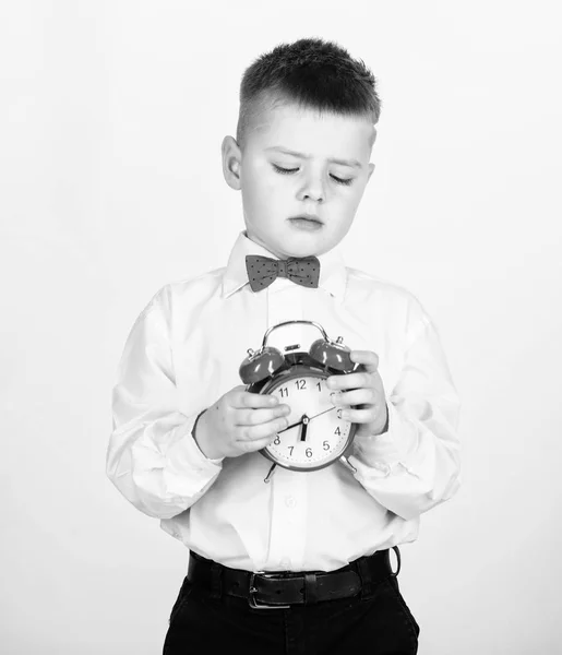 Selbstdisziplin entwickeln. Wecker stellen. Kind kleiner Junge hält rote Uhr. Es ist Zeit. Zeitplan und Timing. Morgenroutine. Schüler mit Wecker. Kind entzückender Junge weißes Hemd rote Fliege — Stockfoto