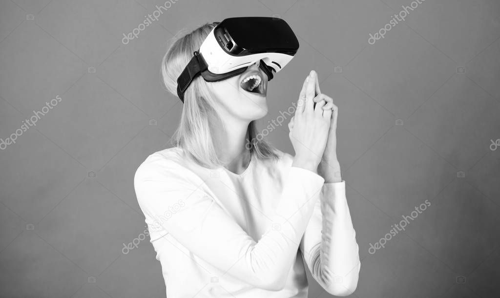 Cheerful smiling woman looking in VR glasses. Woman using VR device. Person with virtual reality helmet isolated on red background. Cyber sport.