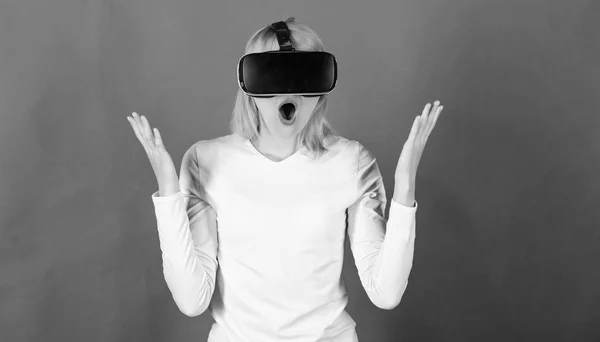 Retrato de una chica sorprendida usando un auricular de realidad virtual aislado sobre fondo rojo. Persona con casco de realidad virtual. Mujer usando auriculares de realidad virtual. Ciencia y futuro . —  Fotos de Stock