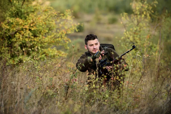 Uomo indossare abiti mimetici sfondo della natura. Permesso di caccia. La caccia è un brutale hobby maschile. Stagioni di caccia e cattura. Il cacciatore serio barbuto spende la caccia di svago. Cacciatore tenere fucile — Foto Stock