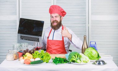 Mutfakta şef dizüstü bilgisayar. Aşçılık okulu. Hipster şapka ve önlük ürünleri online satın almak. Online alışveriş. Adam şef yiyecek pişirme online malzemeler arıyor. Market online. Teslimat hizmeti