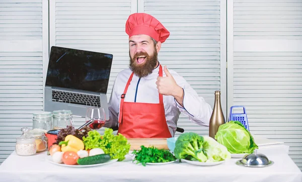 Chef-Laptop in der Küche. Kochschule. Hipster in Hut und Schürze kaufen Produkte online. Online einkaufen. Mann Koch Suche online Zutaten Kochen von Lebensmitteln. Lebensmittelgeschäft online. Lieferservice — Stockfoto