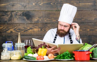 Vejetaryen tarifi. Adam sakallı hipster masa taze sebze yakınında kitap tarifi okuyun. Mutfak sanatları. Tarifi sağlıklı yemek pişirmek için. Deneyimli şef mükemmel yemek pişirme. Bu tarifi sadece mükemmel