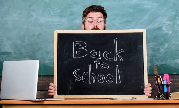 La vie scolaire est pleine de stress. Enseignant ou directeur d'école accueille l'inscription à nouveau à l'école. Homme effrayé début de l'année scolaire. Le professeur jette un coup d'oeil au tableau noir. Éducateur caché derrière le tableau noir — Photo