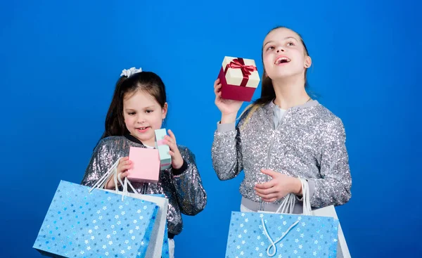 Compras y compras. Viernes Negro. Venta y descuento. Día de compras. Paquetes de niños. Moda infantil. Chicas hermanas amigas con bolsas de compras fondo azul. Cada producto entregado a usted —  Fotos de Stock