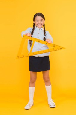 Bir üçgenin üç kenarı ve üç açısı vardır. Sarı arka plan üzerinde üçgen tutan sevimli mutlu okul çocuğu. Geometri dersi için geometrik üçgen ile gülümseyen sevimli kız. Üçgende ders