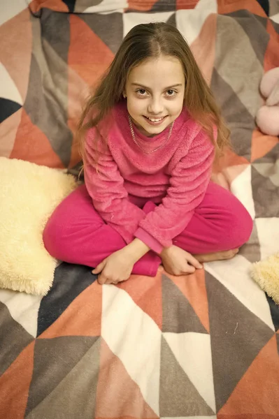 リラックスのための快適なパジャマ。女の子は、ベッドでリラックスしながら摩耗ソフトかわいいパジャマを小さな子供します。リラックスした笑顔の赤ちゃん。パジャマと家のための服。パジャマと寝室繊維。子供は、余暇を楽しむ — ストック写真