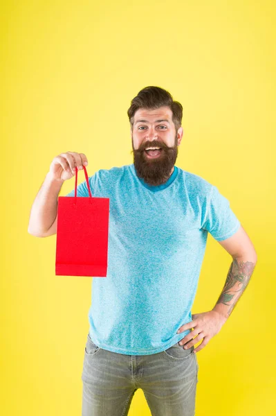 Gender differences in purchase decision making. Happy hipster hold paper bag. Bearded man smiling with fashion purchase. Impulse purchase. Shopping concept. Shop store mall boutique. Buy product