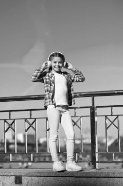 Yeni müzik stillerini keşfetmek, kültürün harika bir yoludur. Kız çocuk açık havada modern kulaklıklarla müzik dinler. Küçük kız şarkı kulaklığı dinliyor. Müzik hesabı çalma listesi. Müziğinizi özelleştirin