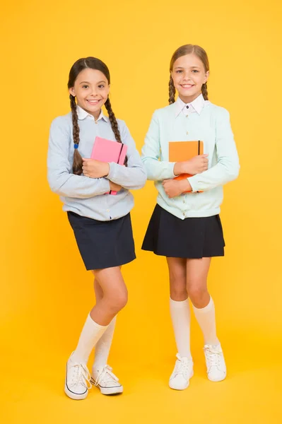 Estudiando literatura inglesa. Niñas sosteniendo libros de lengua y literatura sobre fondo amarillo. Niños pequeños disfrutando de la literatura infantil. Tener clases de literatura en la escuela —  Fotos de Stock