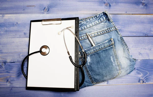 Doctors attributes. Medical insurance. Phonendoscope and paper tablet on jeans background copy space. History of the disease. Medical treatment. Medicine concept. Medical help and consultation