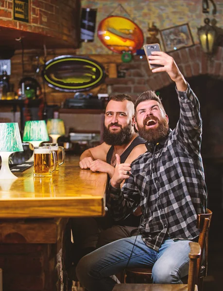 Hombre en el bar bebiendo cerveza. Tome una foto selfie para recordar la gran noche en el pub. Comunicación en línea. Hombre barbudo hipster mantenga el teléfono inteligente. Tomando concepto de selfie. Enviar selfie a amigos redes sociales —  Fotos de Stock
