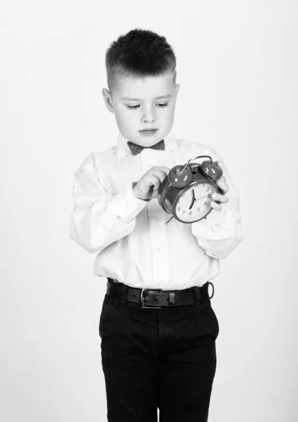 Niño feliz con reloj retro en corbata de lazo. niño pequeño con despertador. Es hora de relajarse. Hora de la fiesta. Empresario. Ropa formal. Gestión del tiempo. Buenos días. Esmoquin. Feliz infancia. Memorable mañana —  Fotos de Stock