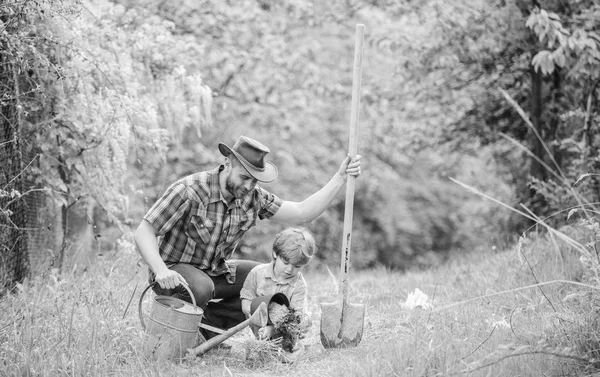 Heureux jour de la terre. pépinière d'arbre généalogique. arrosoir, pot et pelle. Équipement de jardin. Eco ferme. petit garçon enfant aider père dans l'agriculture. père et fils en chapeau de cow-boy sur ranch. Sous le temps — Photo