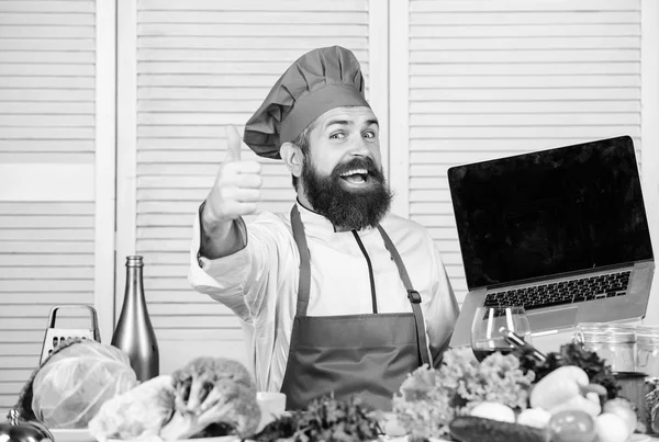 Online winkelen. Man chef zoeken online ingrediënten koken voedsel. Levensmiddelenwinkel online. Bezorgservice. Chef-kok laptop in de keuken. Culinaire school. Hipster in hoed en schort Koop producten online — Stockfoto