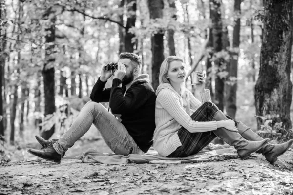 Relaxing in park together. Happy loving couple relaxing in park together. Couple in love tourists relaxing picnic blanket. Man with binoculars and woman with metal mug enjoy nature park. Park date