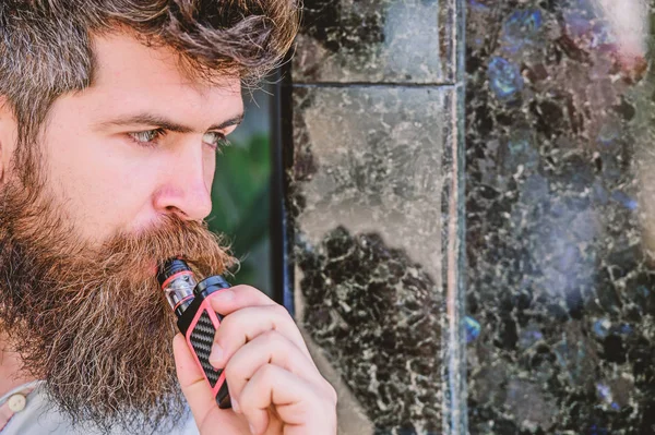 Bearded man smoking vape. Man with beard breathe out smoke. Smoking electronic cigarette. Stress relief concept. Smoking device. Man long beard relaxed with smoking habit. Clouds of flavored smoke