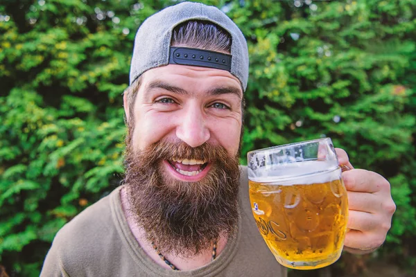 Potrzebuję zimno jeden. Szczęśliwy Hipster trzyma kubek piwa. Brodaty człowiek szczęśliwy uśmiechnięty z piwem na łonie natury. Szczęśliwy pijący. Piwo jest dowodem na to, że Bóg chce, abyśmy byli szczęśliwi — Zdjęcie stockowe