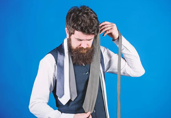 Hard choice to make. Bearded man choosing tie from luxury collection, choice concept. Salesman offering a good choice of design neckties. Brutal hipster making a choice