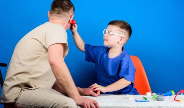 Hastane çalışanı. Sağlık. Tıp kavramı. Çocuk küçük doktor masa tıbbi aletleri oturup. Hastalık tedavisi. Baba ve oğul tıbbi hanedan. Tıbbi muayene. Çocuk sevimli çocuk ve babası doktor