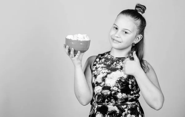 Menina sorrindo tigela rosto hold com doce marshmallows na mão bege fundo. Conceito dos dentes doces. Miúda com cabelos longos gosta de doces e guloseimas. Calorias e dieta. Miúdo faminto. Desafio Marshmallow — Fotografia de Stock