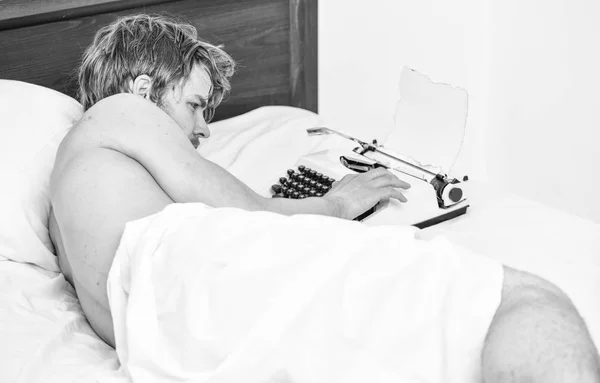 Man writer lay bed working on new book. New day brings fresh ideas. Writer author used old fashioned machine instead of digital gadget. Morning inspiration. Writer use manual typewriter daily work