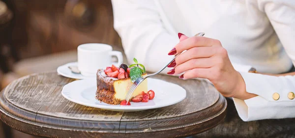Десертный торт чашку кофе и женскую руку с вилкой крупным планом. Проще простого с красной ягодой. Еда по рецепту гурманов. Кусочек торта на белой тарелке. Торт со сливочным десертом. Концепция аппетита — стоковое фото