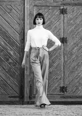 Makyajlı kız moda kıyafetlerle poz yapıyor. Moda kıyafeti ince uzun boylu bayan. Kadın kendinden emin bir şekilde yürüyor. Kadın moda esmer standı açık ahşap arka plan. Moda ve stil konsepti