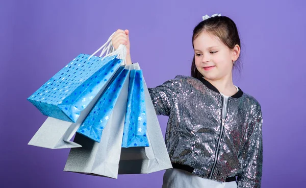 Akciós árengedmény. Bevásárló-nap. Gyermek ragaszkodik csokor csomagokat. Gyerekek divat. Születésnapi lány. Meglepetés ajándék. Lány bevásárló táskák lila háttérrel. Vásárlás és vásárlás. Kap jobb látszó. Fekete péntek — Stock Fotó