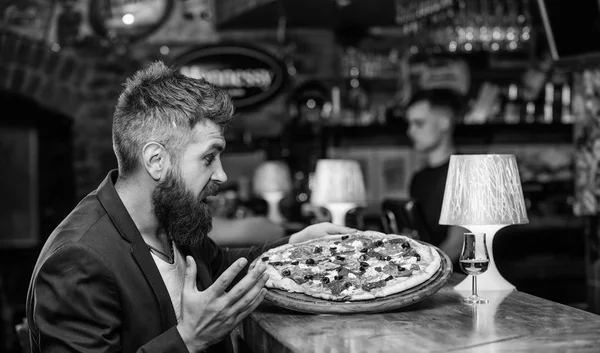 Cheat meal concept. Hipster hungry eat italian pizza. Pizza favorite restaurant food. Fresh hot pizza for dinner. Hipster client sit at bar counter. Man received delicious pizza. Enjoy your meal