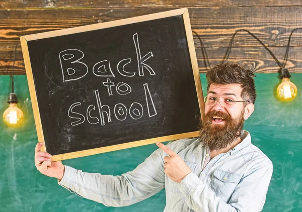 Вчителька в окулярах тримає дошку з заголовком назад до школи. Чоловік з бородою і вусами на щасливому обличчі вітає колег, крейдяну дошку на фоні. Концепція найму вчителів — стокове фото