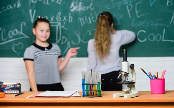 Chemical reactions. Make studying chemistry interesting. Pupil at chalkboard on chemistry lesson. Educational experiment concept. Girls classmates study chemistry. Microscope and test tubes on table — Stock Photo, Image
